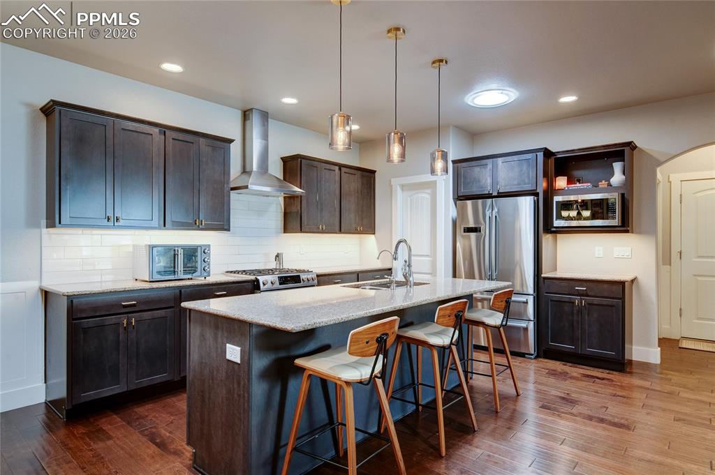 Image 11 of 44: Kitchen with a kitchen breakfast bar, decorative backsplash, pendant lighti