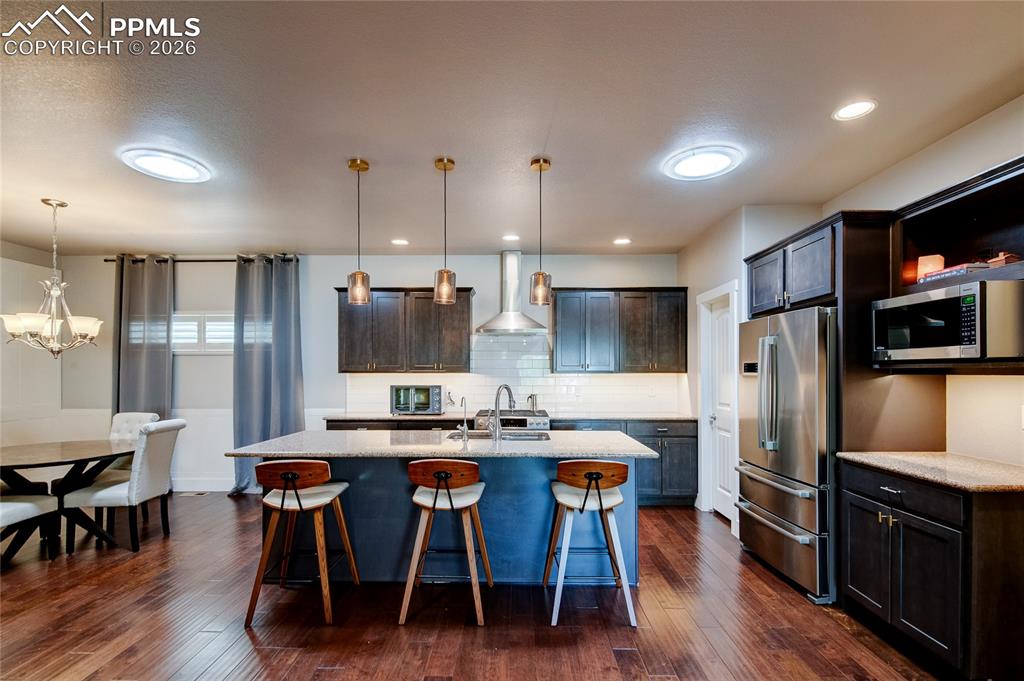 Image 19 of 44: Kitchen with a kitchen bar, stainless steel appliances, pendant lighting, d