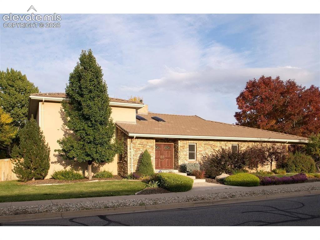 Caption: Stucco and stone exterior featuring double-entry front doors, a tiled roof, and integrated skylights
