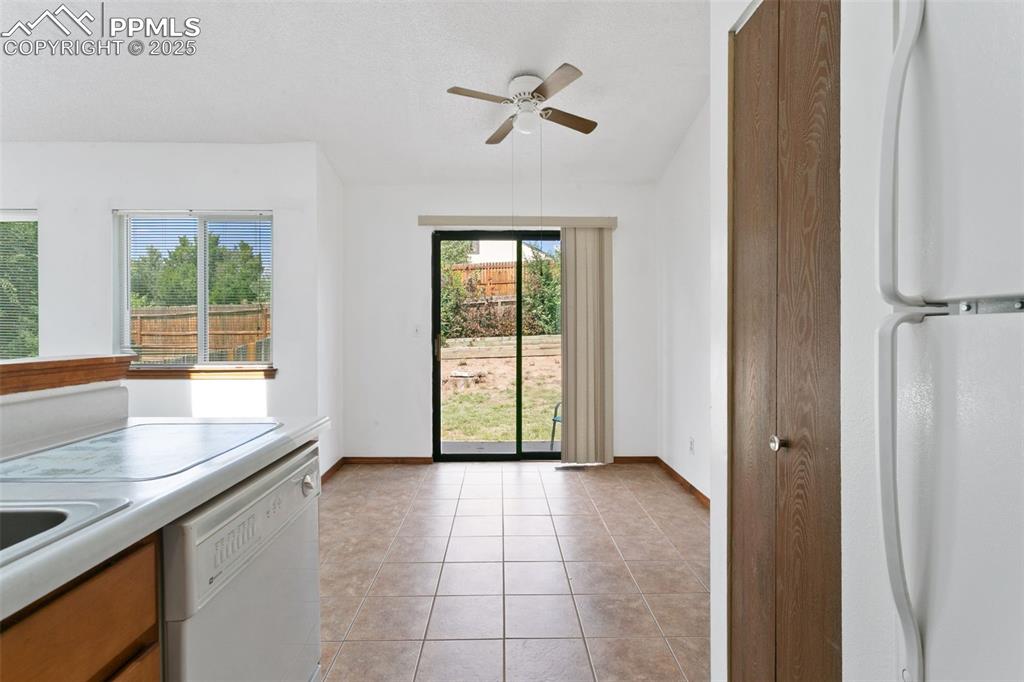 Image 11 of 24: Kitchen with white appliances, light tile patterned flooring, light counter