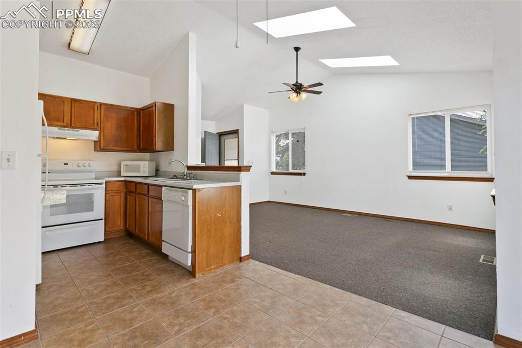 Image 12 of 24: Kitchen with light colored carpet, white appliances, light tile patterned f