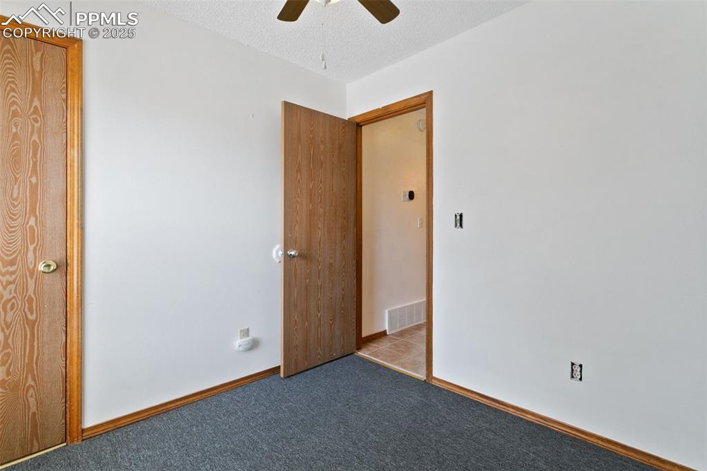 Image 21 of 24: Unfurnished bedroom featuring a textured ceiling, a ceiling fan, and carpet