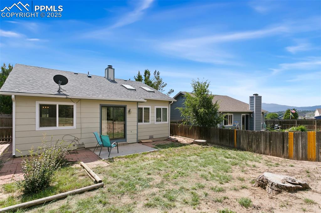 Image 24 of 24: Back of property featuring a fenced backyard, a patio, a chimney, and a shi