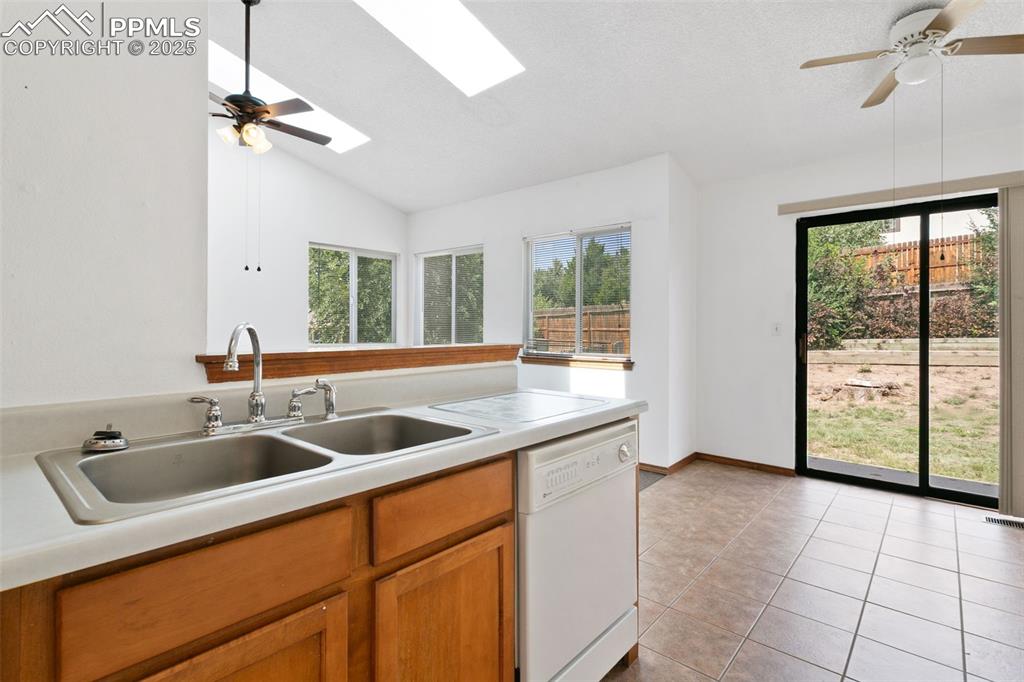 Image 5 of 24: Kitchen featuring a ceiling fan, dishwasher, vaulted ceiling, brown cabinet