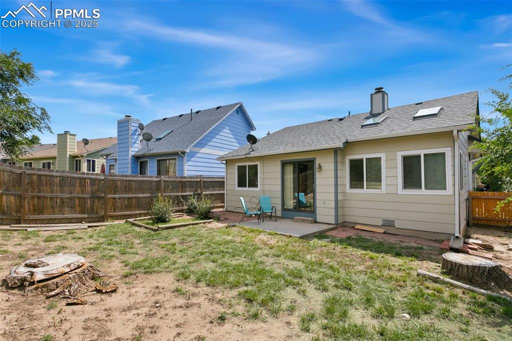 Image 6 of 24: Back of property featuring a fenced backyard, a patio, roof with shingles, 