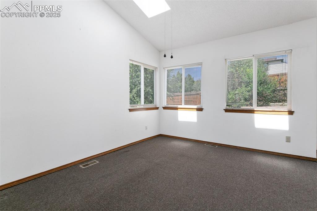 Image 8 of 24: Carpeted spare room featuring vaulted ceiling and a skylight