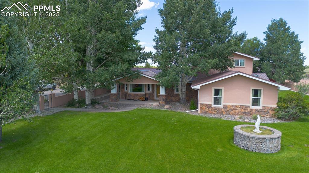 Image 1 of 50: Back of house with stone siding, stucco siding, and covered porch