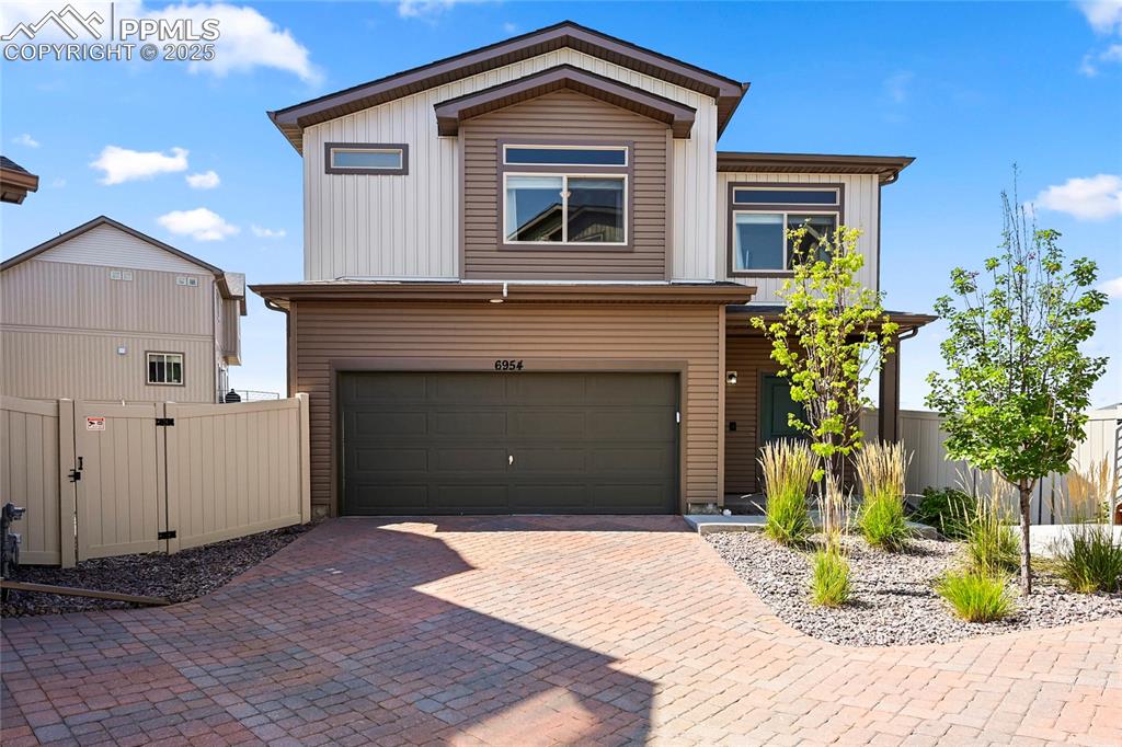 Caption: View of front of house featuring decorative driveway and an attached garage
