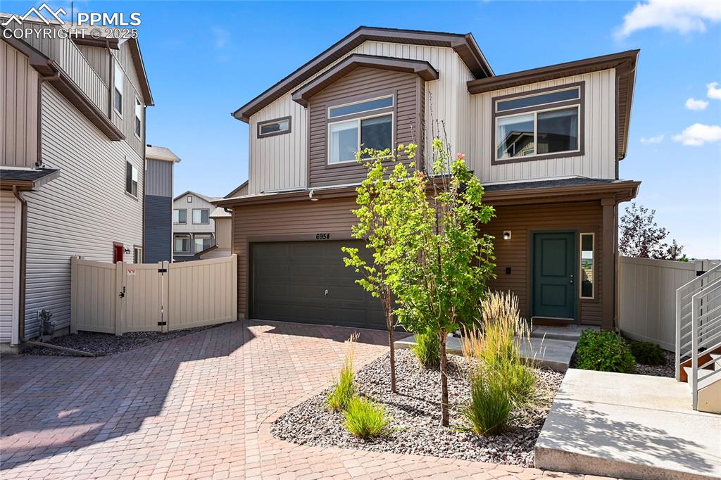 Image 2 of 28: View of front facade featuring a gate, decorative driveway, an attached gar