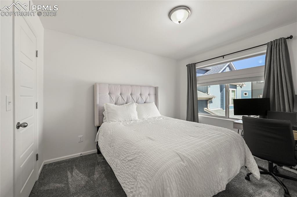 Image 20 of 28: Bedroom with dark carpet and a desk