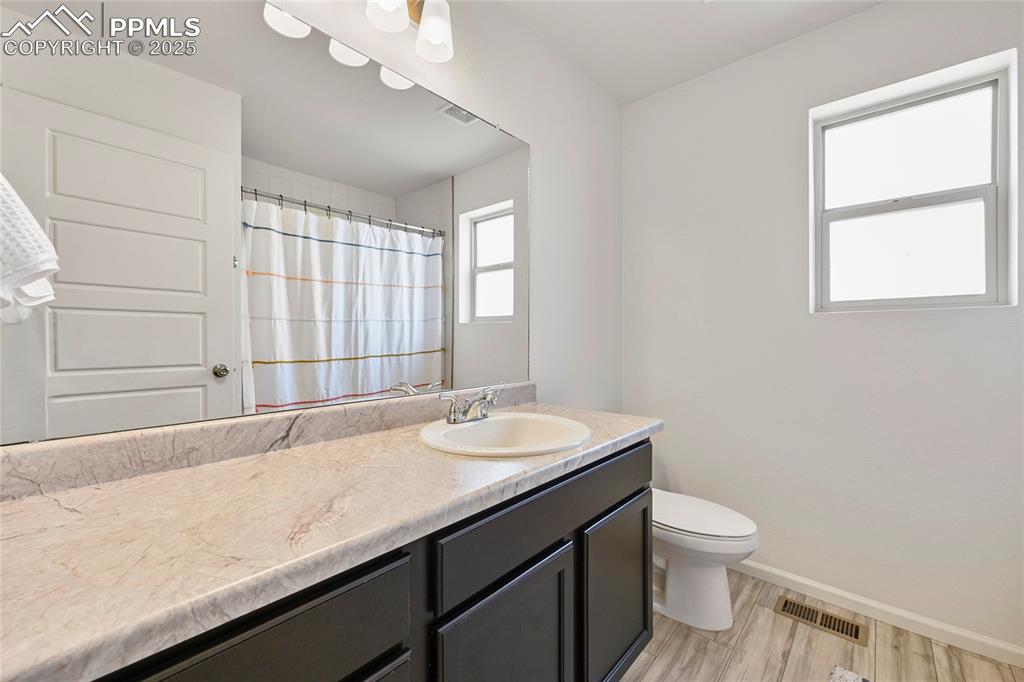 Image 24 of 28: Bathroom with vanity, light wood-style floors, and curtained shower
