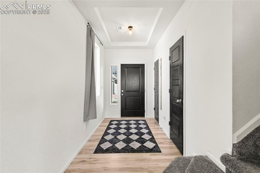 Image 5 of 28: Doorway with a raised ceiling and wood finished floors
