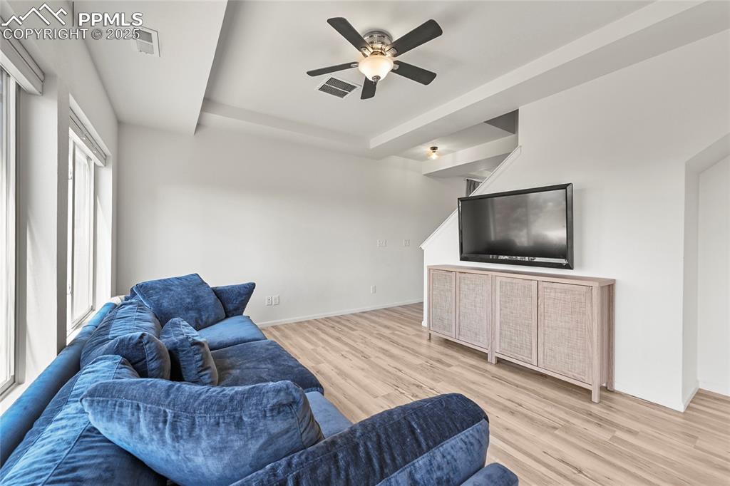 Image 8 of 28: Living area featuring light wood finished floors and a ceiling fan