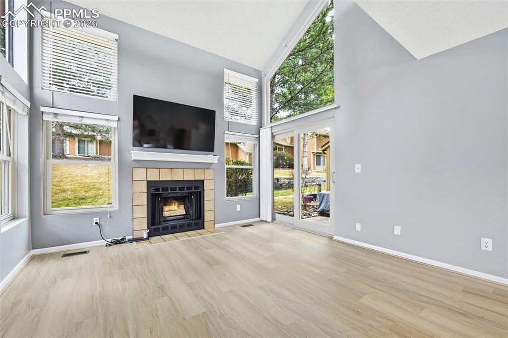 Image 5 of 30: The vaulted living room features a walk-out patio & cozy wood-burning firep