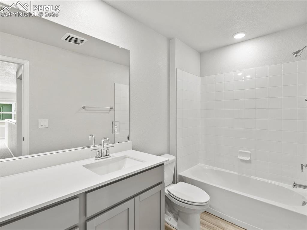 Image 18 of 28: Bathroom with vanity, shower / bathtub combination, wood finished floors, a