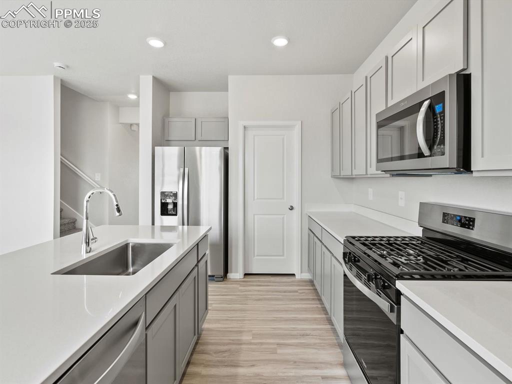 Image 4 of 28: Kitchen with stainless steel appliances, light wood-type flooring, gray cab