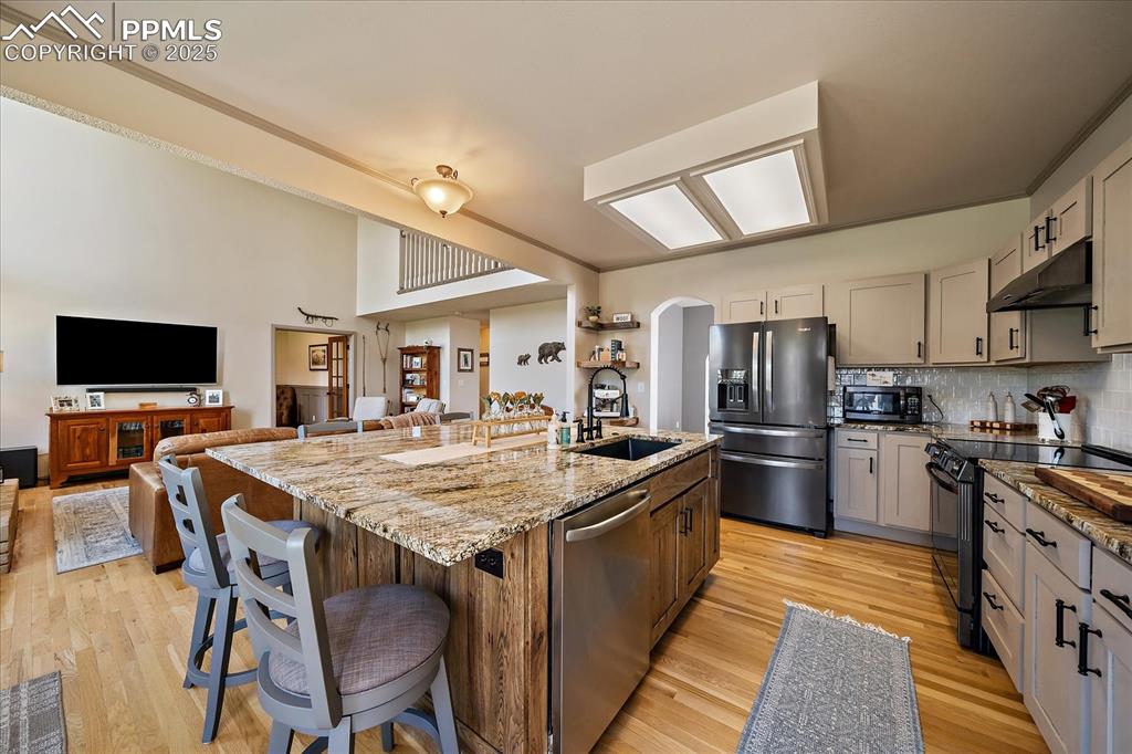 Image 13 of 47: Kitchen featuring black appliances, a sink, under cabinet range hood, and l