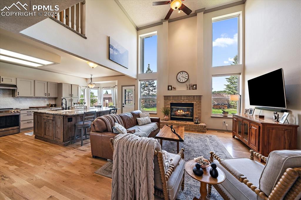 Image 15 of 47: Living room with a high ceiling, crown molding, light wood-style flooring, 