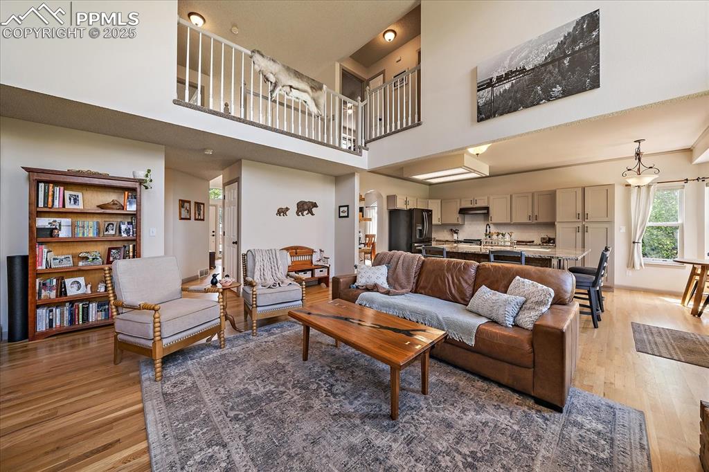 Image 16 of 47: Living room with light wood-style flooring, a towering ceiling, and baseboa