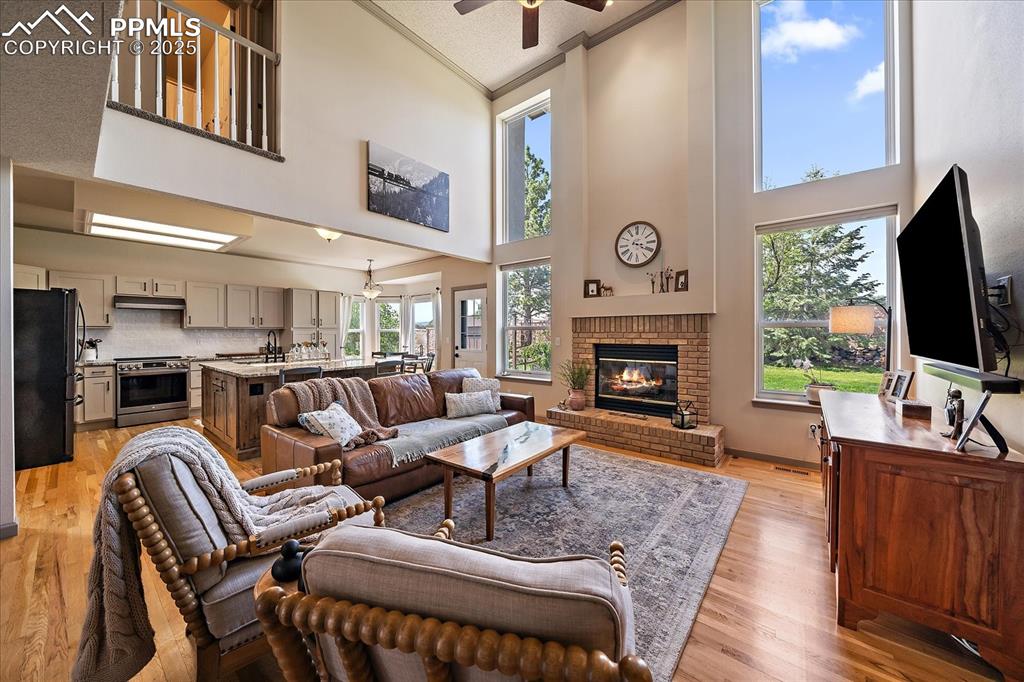 Image 17 of 47: Living room featuring high vaulted ceiling, ceiling fan, a brick fireplace,