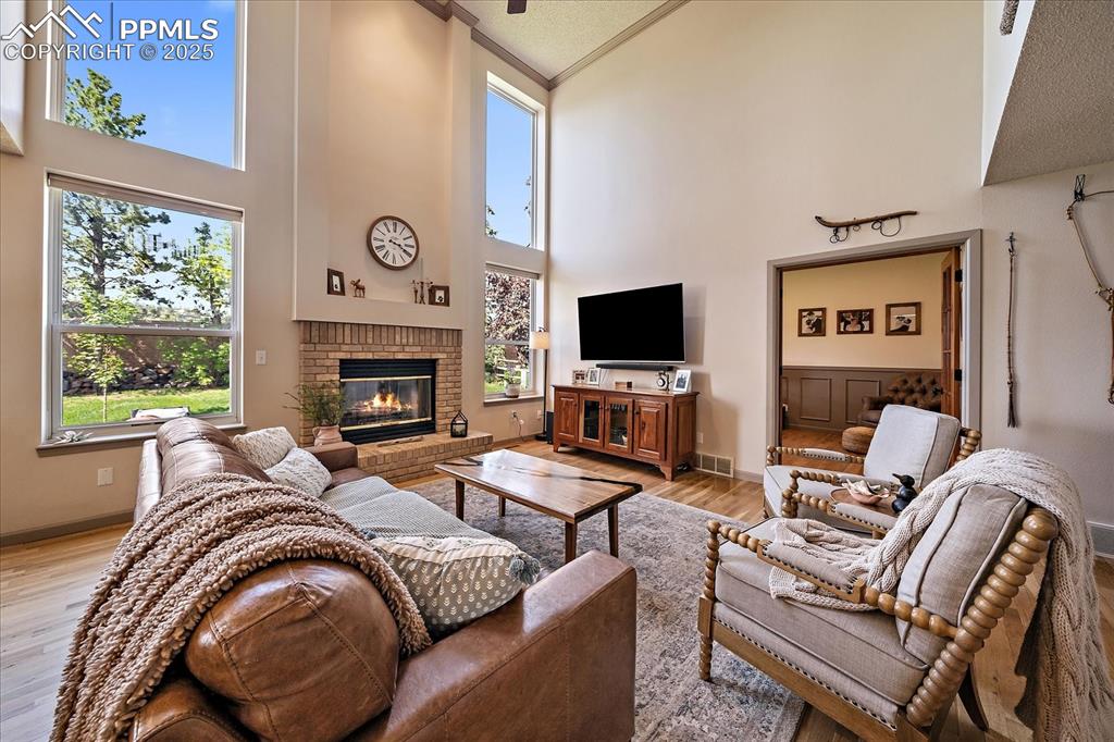 Image 18 of 47: Living area featuring a high ceiling, light wood-style floors, a brick fire
