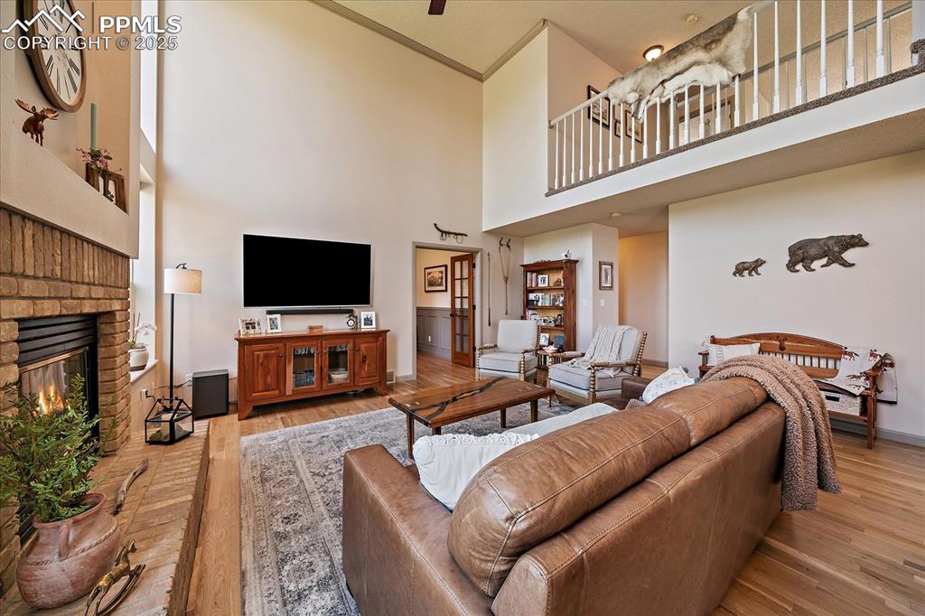 Image 19 of 47: Living room with a towering ceiling, light wood finished floors, a brick fi