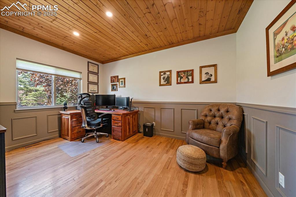 Image 20 of 47: Office space featuring a wainscoted wall, ornamental molding, and light woo