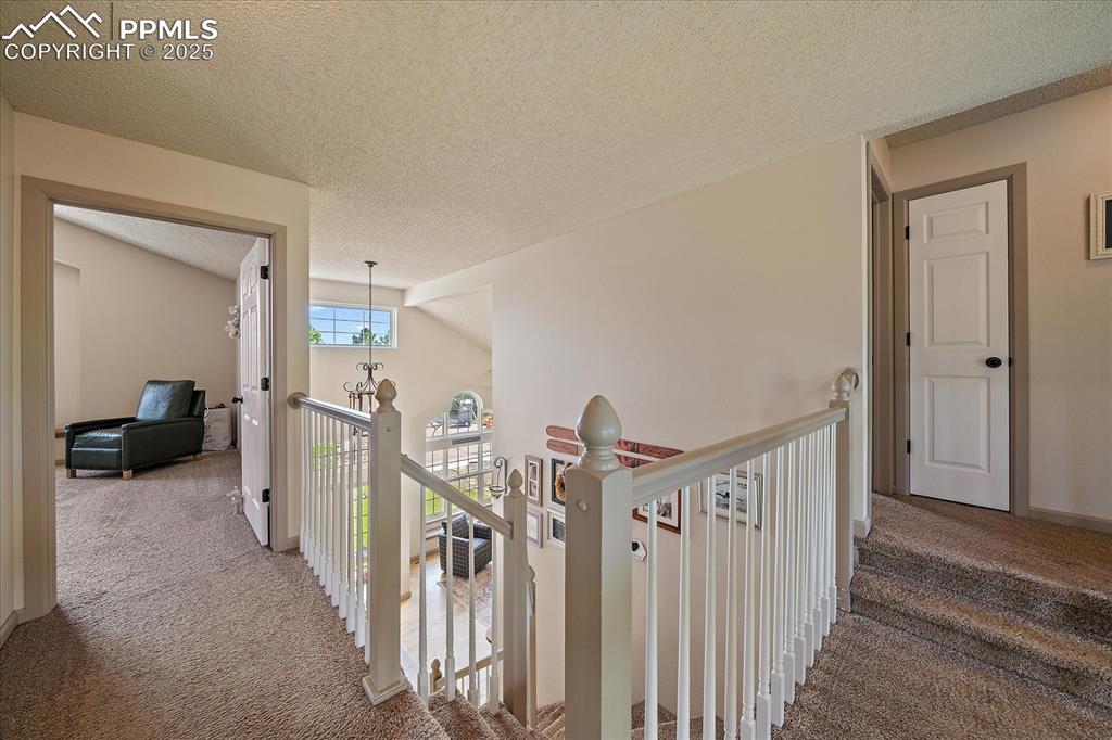 Image 23 of 47: Hall with carpet, an upstairs landing, and a textured ceiling