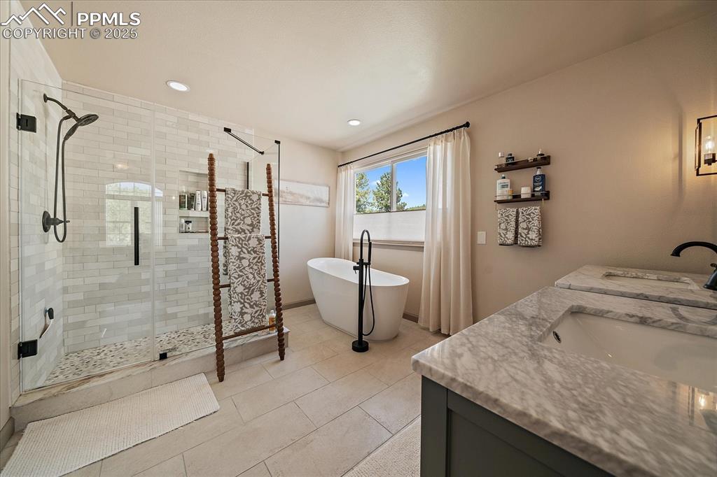 Image 28 of 47: Bathroom featuring a stall shower, double vanity, a freestanding bath, tile