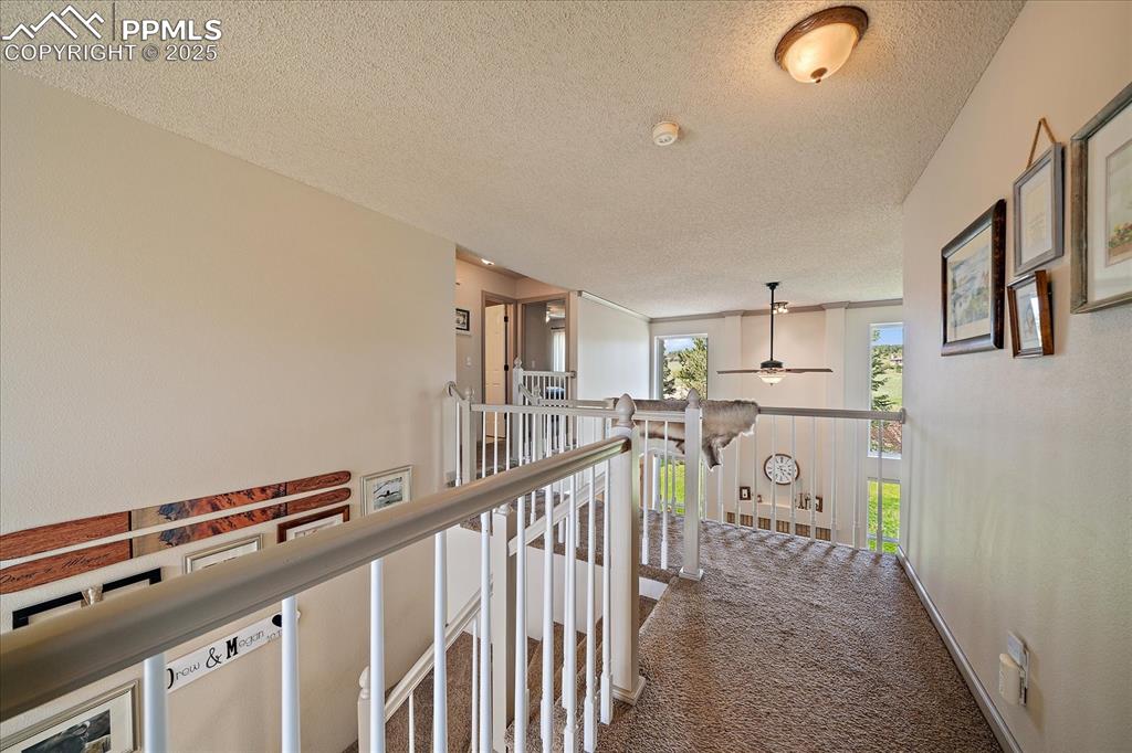 Image 29 of 47: Corridor featuring an upstairs landing, a textured ceiling, and carpet floo