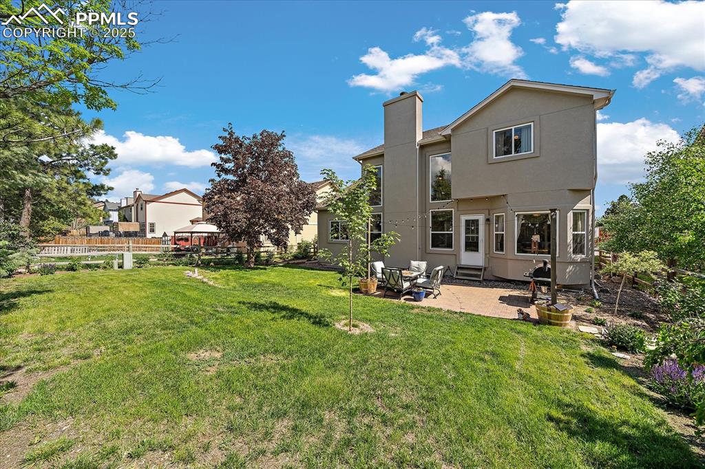 Image 3 of 47: Back of property featuring entry steps, a patio area, a chimney, and stucco