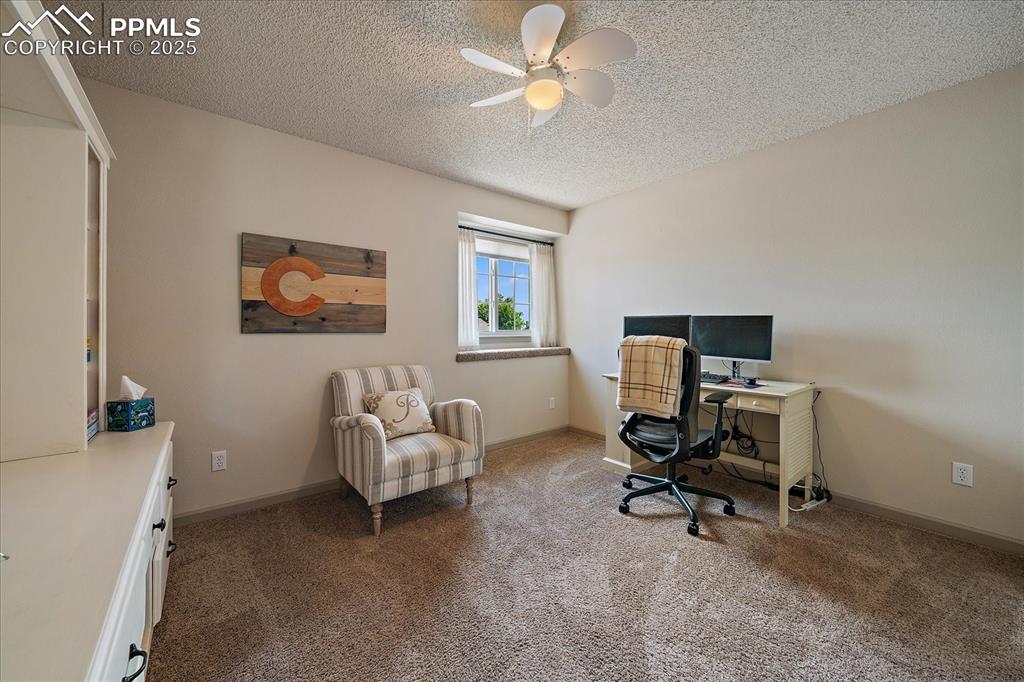 Image 31 of 47: Office area featuring carpet, a textured ceiling, a ceiling fan, and basebo