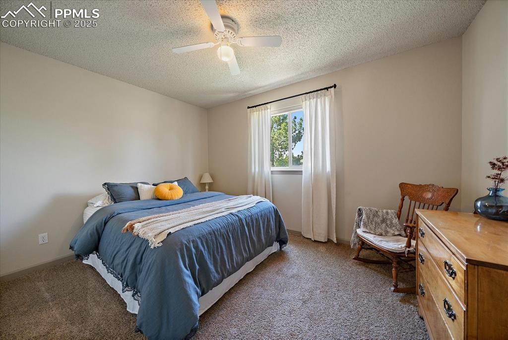 Image 33 of 47: Carpeted bedroom with a textured ceiling, a ceiling fan, and baseboards