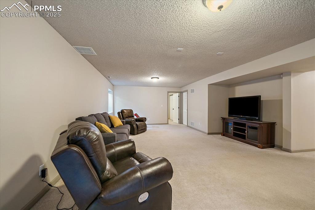 Image 35 of 47: Carpeted living room with a textured ceiling and baseboards