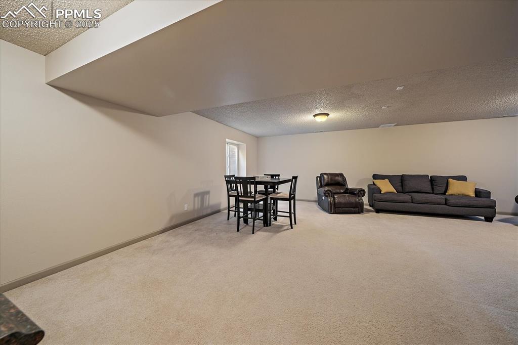 Image 36 of 47: Carpeted living room with a textured ceiling and baseboards
