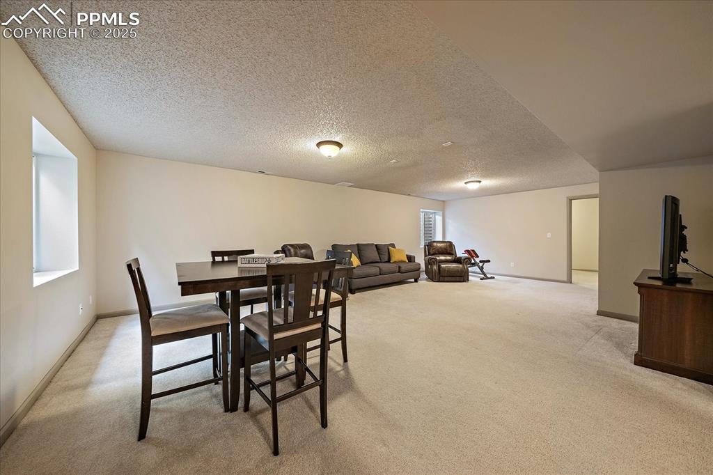 Image 37 of 47: Dining room with light carpet, a textured ceiling, and baseboards