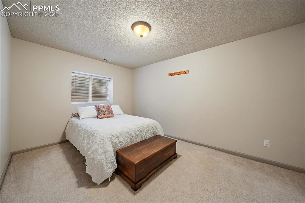 Image 41 of 47: Bedroom featuring light colored carpet, baseboards, and a textured ceiling