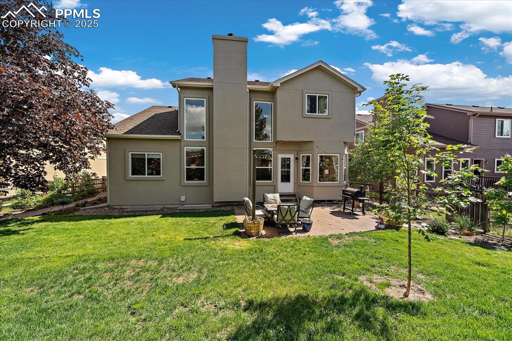 Image 42 of 47: Back of property featuring a chimney, a patio area, stucco siding, and roof