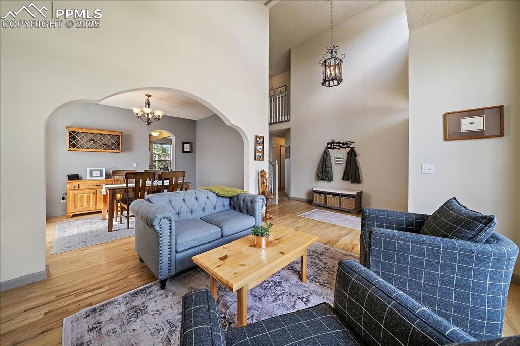 Image 8 of 47: Living room with arched walkways, a chandelier, light wood-type flooring, a