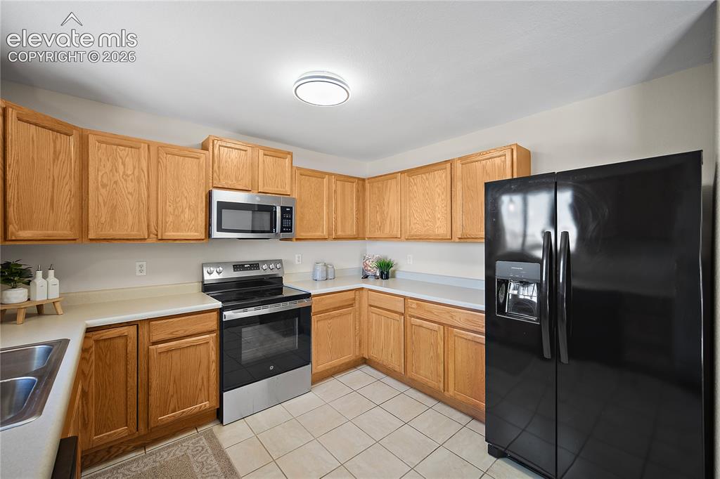 Image 10 of 29: Kitchen featuring wood-finish cabinetry, light-toned countertops, and tile