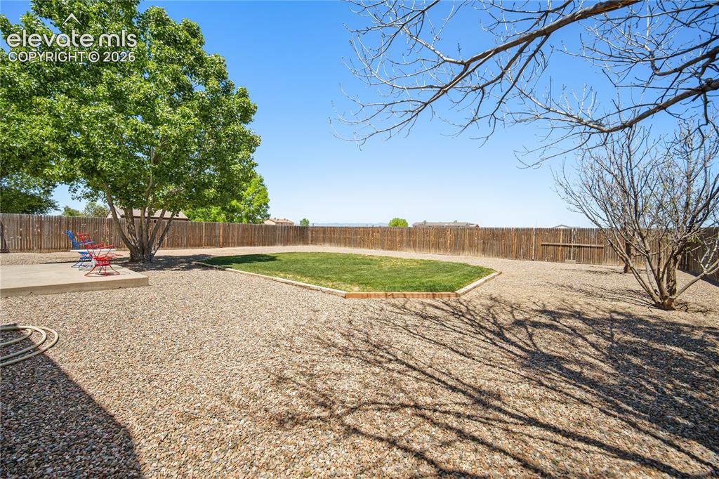 Image 22 of 29: Expansive rear yard featuring a gravel surface, a central lawn area, and ma