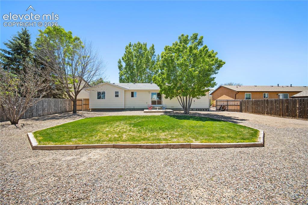 Image 24 of 29: Ranch-style residence featuring a prominent mature tree, an attached two-ca