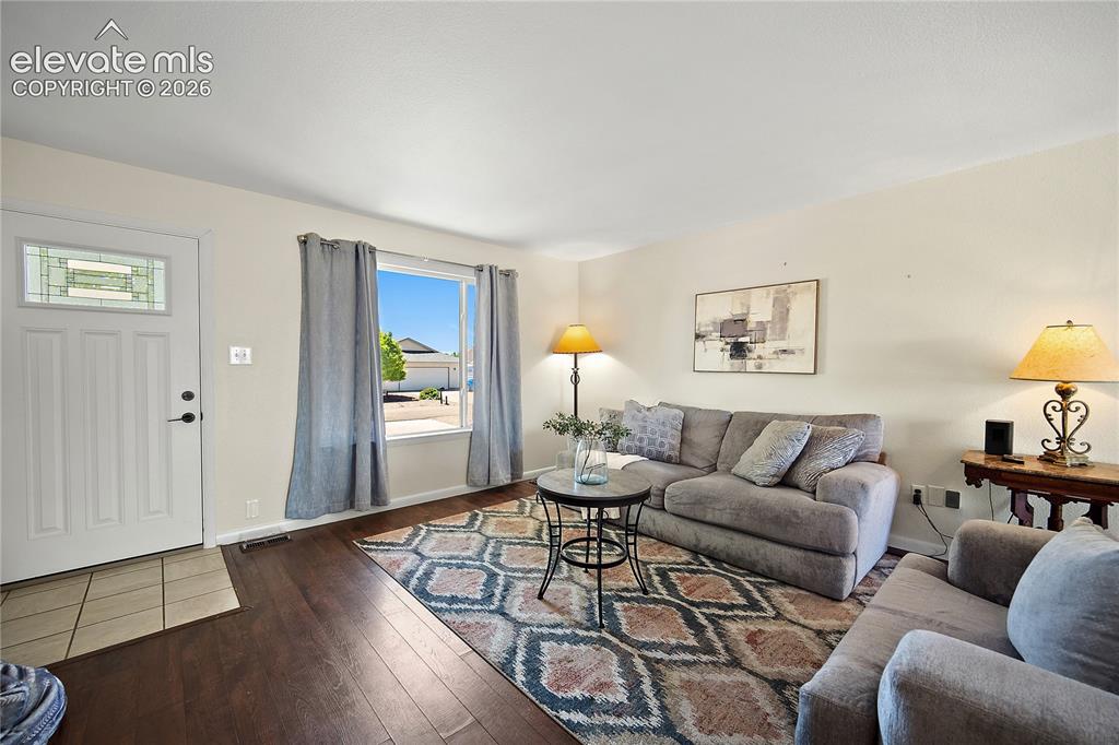 Image 5 of 29: Spacious living area featuring wood-finish flooring and a large window prov