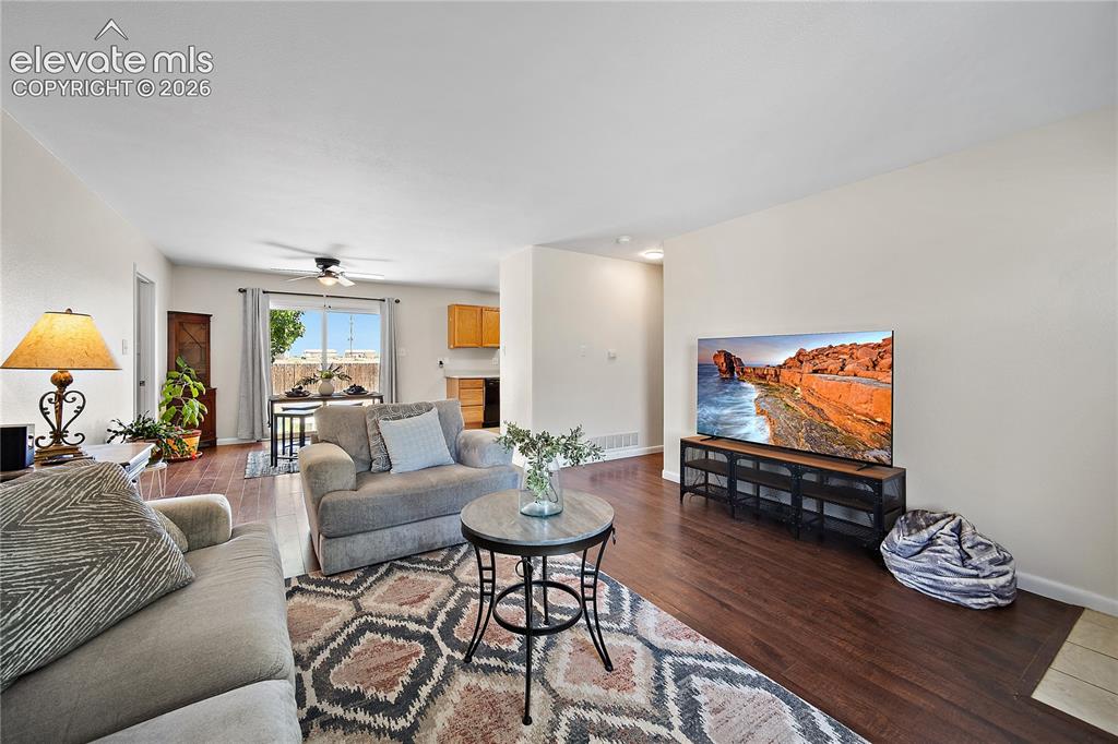 Image 6 of 29: Living area featuring rich wood-finish flooring, light-toned walls, and a l