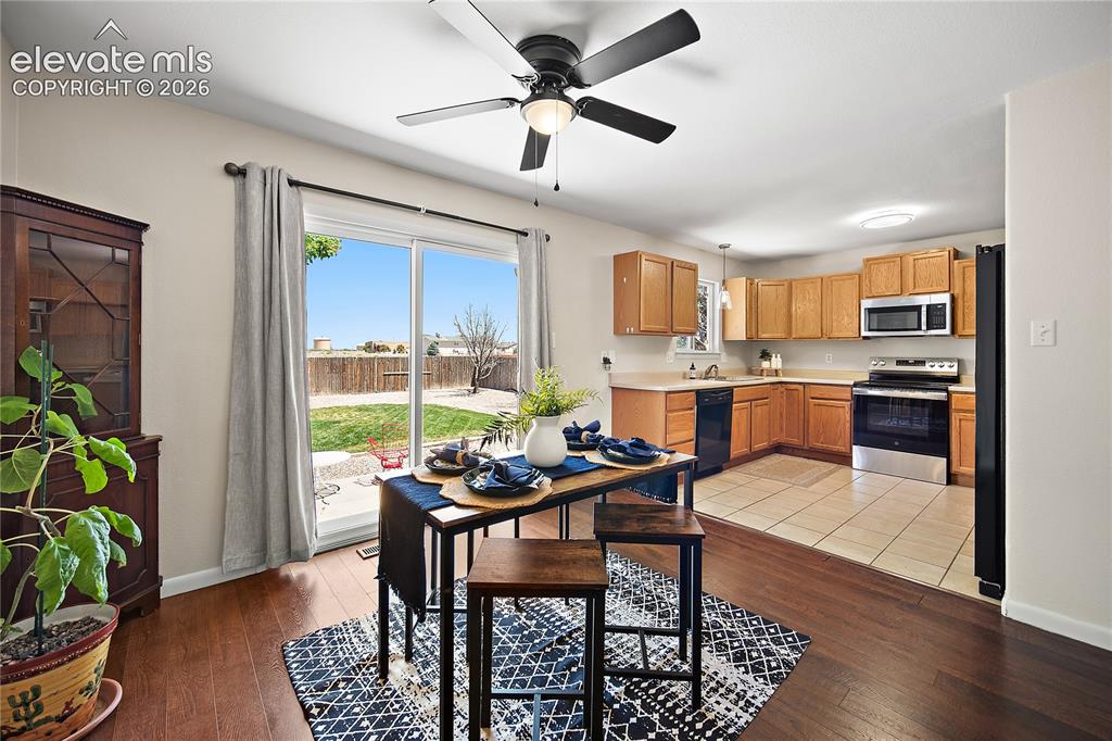 Image 8 of 29: Open-concept dining area with wood-finish flooring, a ceiling fan, and slid