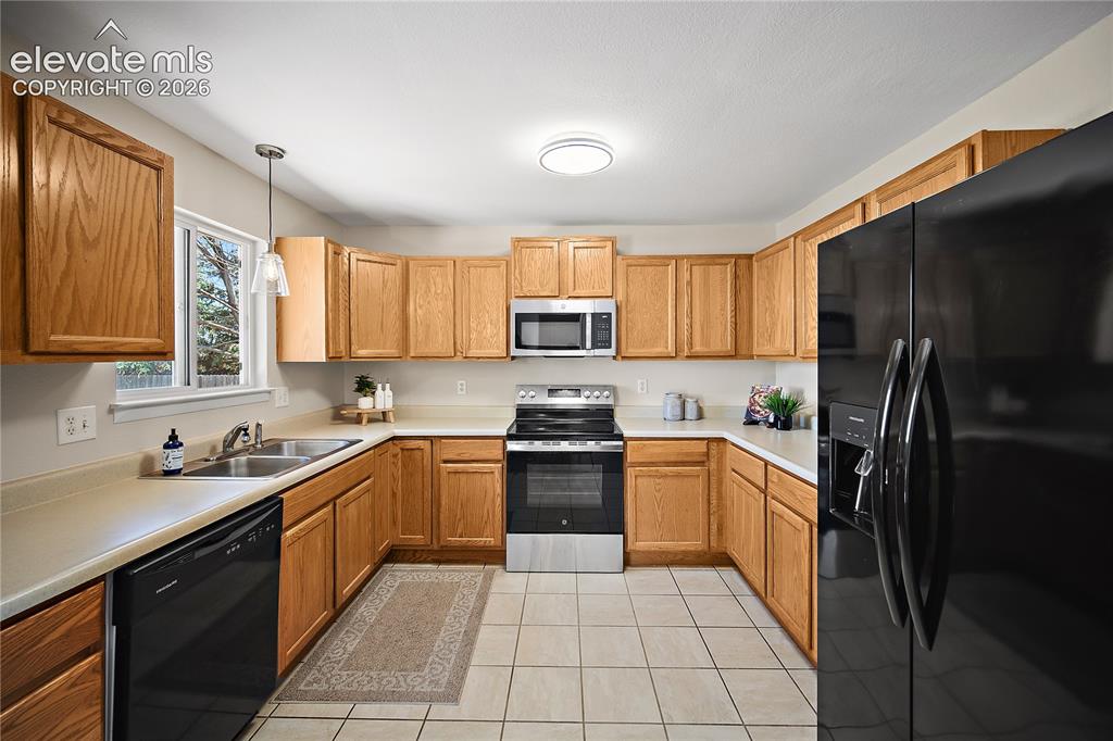 Image 9 of 29: U-shaped kitchen featuring light wood cabinetry, light-toned countertops, a
