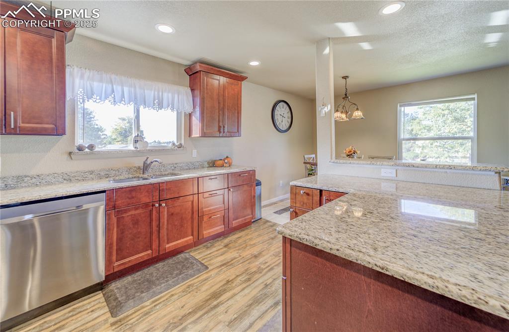 Image 10 of 25: Kitchen featuring light wood-type flooring, light stone countertops, stainl