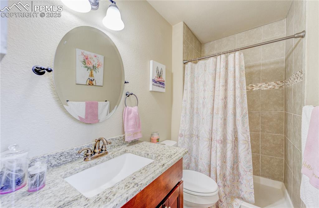 Image 16 of 25: Bathroom with walk in shower, vanity, and toilet