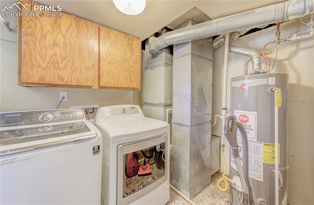Image 17 of 25: Laundry area featuring cabinets, gas water heater, independent washer and d