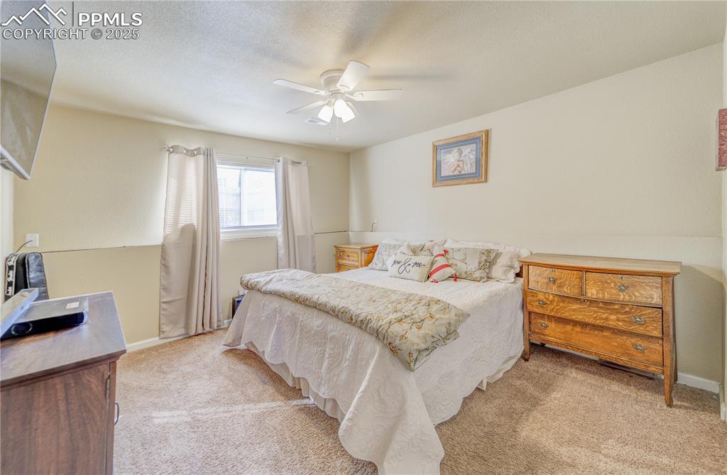 Image 18 of 25: Bedroom with ceiling fan, light colored carpet, and a textured ceiling